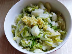 将捣好的梨放入切好的白菜器具中，姜去皮切小放入捣蒜泥器具中，捣成姜末加入白菜中。