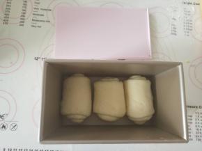 11、从上往下卷起，收紧封口处。放入学厨土司盒中进行二发。