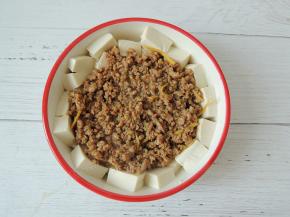 将炒好的肉末盛入装有豆腐的碗里面，铺平。