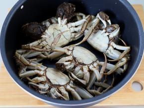 螃蟹清洗干净以后，腹部朝上放入电饭煲的甑锅里面。