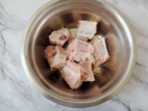 将猪肋排捞出来，沥干水分，然后用厨房纸巾将排骨表面的水分擦一下，再放入搅拌用的大碗中。