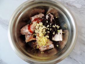 放入生姜末、大蒜末和少许白胡椒粉，将豆豉碎也放入排骨中。