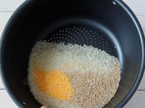 将大米、藜麦和玉米渣倒入甄锅里面，淘洗干净。甄锅底部有小孔，可以直接用来淘米。