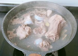 锅里加适量清水，加筒骨，生姜片一起焯水2分钟。焯水后的筒骨清洗一下。