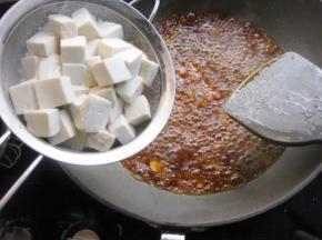 7 接着倒入1碗水里面煮开，然后把之前煮好的豆腐沥出来，倒进锅里面。盖上盖子焖煮6分钟左右
