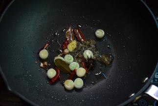 锅中留适量底油，中小火将冰糖、葱段、八角等煸炒爆香