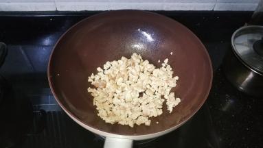 锅里热油放入腌好的鸡胸肉碎炒均匀