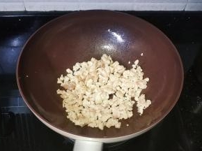 锅里热油放入腌好的鸡胸肉碎炒均匀