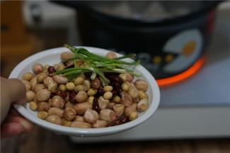 再将泡洗好的黄豆，花生及花芸豆还有葱段下砂锅，再加入料酒一并炒炒香。