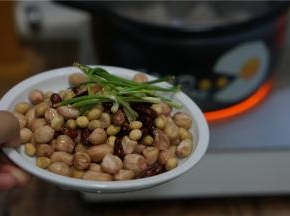 再将泡洗好的黄豆，花生及花芸豆还有葱段下砂锅，再加入料酒一并炒炒香。