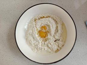 低粉和玉米淀粉过筛入盆中，加入鸡蛋，玉米油和牛奶搅拌成面絮状