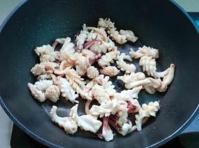 锅中热点油，放入鱿鱼卷炒几下，加料酒、酱油和盐炒匀