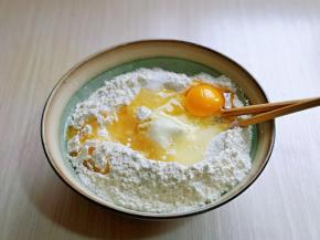 加入玉米油，盐，鸡蛋，搅拌均匀，再分次加入温水，搅拌成絮状。