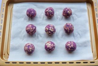 取适量紫薯泥，搓成小球，放在铺了烘焙纸的烤盘上。