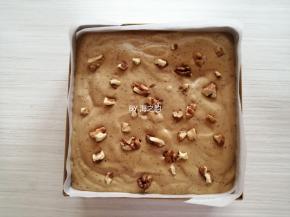 把蛋糕糊倒入已经铺了油纸的法焙客加高方形蛋糕模具里，在桌面上震出气泡，表面撒上核桃碎装饰