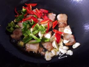 肉片变色后，放入青红椒和蒜片翻炒均匀