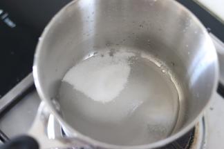 首先来制作焦糖，糖和水混合，热水最后加，放入小锅中，开小火，晃动锅子，让水和糖混合。