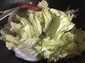将白菜菜梗炒至稍微透明变软后，将白菜叶子滤干水份，倒入锅中，继续大火翻炒；