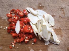 趁着浸泡白菜的时间，将红辣椒清洗干净切碎，再将大蒜剥皮，切成薄片；