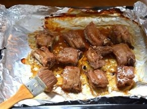 7 将烤盘端出，表面的锡纸去掉，用刷子蘸剩余的酱汁刷在排骨表面；