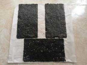 所有的海苔全部加芝麻擀好后，放到油纸上。这个时候去预热烤箱，上下火90度5分钟