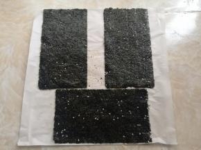 所有的海苔全部加芝麻擀好后，放到油纸上。这个时候去预热烤箱，上下火90度5分钟