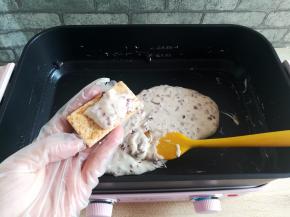 戴一次性手套，捏一小块炒好地牛扎夹心放到一块咸蛋黄方块酥饼干中间