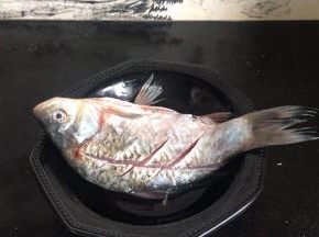 鲫鱼清理干净后，划上花刀，淋入料酒，抹上盐，腌制一小时