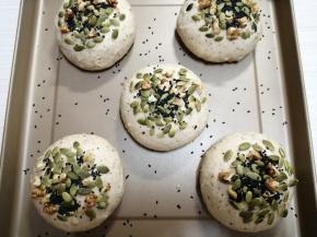 在发酵好的面包胚喷水，把南瓜子仁、核桃和芝麻粘在表面