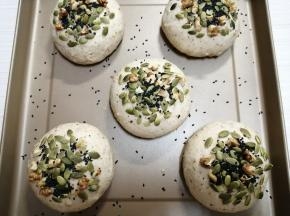在发酵好的面包胚喷水，把南瓜子仁、核桃和芝麻粘在表面