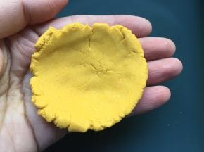 取适量面团，利用双手掌心稍微揉成球，再用双手掌心对压按扁，再用手指将面饼边缘稍微捏薄，形成中间厚边缘薄;