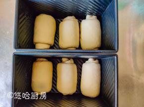 二次醒发后的面团上下擀开，翻面后卷起，接口朝下放入吐司模具中，盖保鲜膜放入烤箱进行二次醒发，烤箱里面要放一碗热水，来提高温度和湿度。