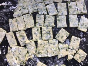 在案板上撒上一层薄薄的面粉或者抹上适量的食用油防沾，将面团擀成大面片，再用刀切成小碎片备用；