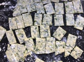 在案板上撒上一层薄薄的面粉或者抹上适量的食用油防沾，将面团擀成大面片，再用刀切成小碎片备用；
