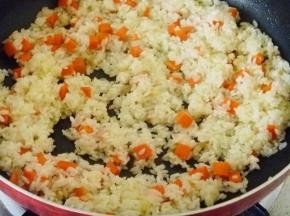 10 萝卜丁翻炒均匀后放入洗好的大米，翻炒大米均匀粘上油脂稍微干一些即可。