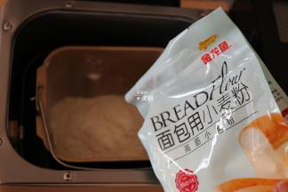 将面团材料中的纯牛奶和鸡蛋液倒入面包机的面包桶中，盐、白砂糖对角放，倒入金龙鱼面包用小麦粉，这个粉采用100%进口小麦为原料，麦香浓郁，制作过程中易膨胀易拉丝，吸水性也好，面粉质量稳定性较好，成品香软可口；