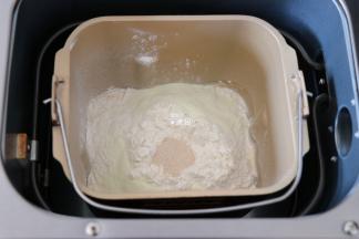 四周再倒入奶粉，粉中间挖个洞放入干酵母粉，启动面包机和面程序开始揉面；