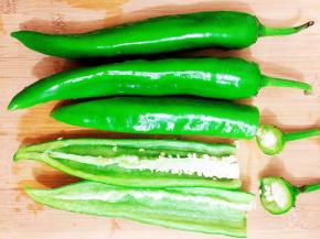 尖椒洗干净，把尖椒的头部切掉一点点，接着用小刀对半切开，去除辣椒籽