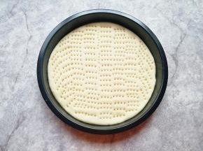 擀成一张和模具大小一致的面饼，放进披萨盘里，用叉子扎满小孔，防止饼皮在烤制的过程中中间凸起。