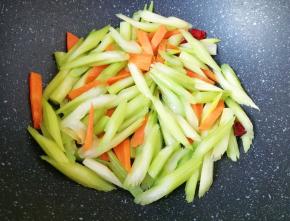 下入芹菜和胡萝卜翻炒至变色。
