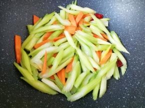 下入芹菜和胡萝卜翻炒至变色。