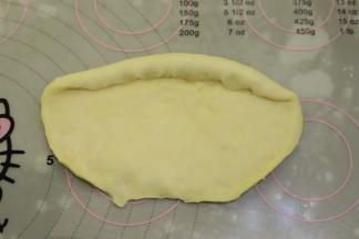 取一小份面团，擀成椭圆形，翻面，转90度角，底部压平。