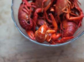 4 龙虾入开水中煮熟。小龙虾的尾部用剪刀剪一条缝，以便做时入味。