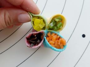 然后在每个花瓣里放入不同颜色的装饰蔬菜碎，然后在每瓣上捏一下。