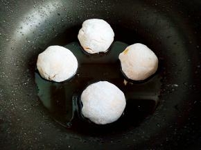 手上抹面粉，揪出小剂子，揉圆入油锅煎制。