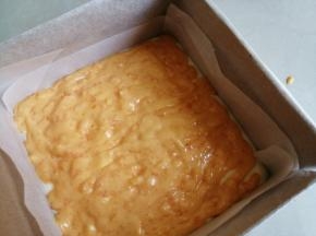 把1/2的蛋糕糊倒入法焙客18CM加高正方形不粘蛋糕模里（烤盘提前铺上油纸，并在四周插上纸板），把咸蛋黄流心酱挤在表面