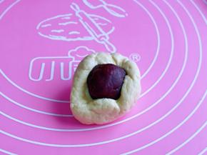 取一块面团，用手掌心压扁，再放上豆沙馅，虎口手法包起来，收口捏紧。