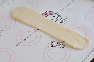 再一次将布置擀成细长的牛舌状，翻面后，由上至下卷起。