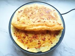 油条从中间撕开，放一半在煎饼上面。
