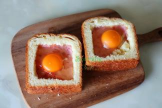 放凉的吐司切厚片，用刀叉在吐司中间挖一个火腿片大小的方块，然后放入芝士、火腿片、再倒入鸡蛋，表面撒些胡椒粉。